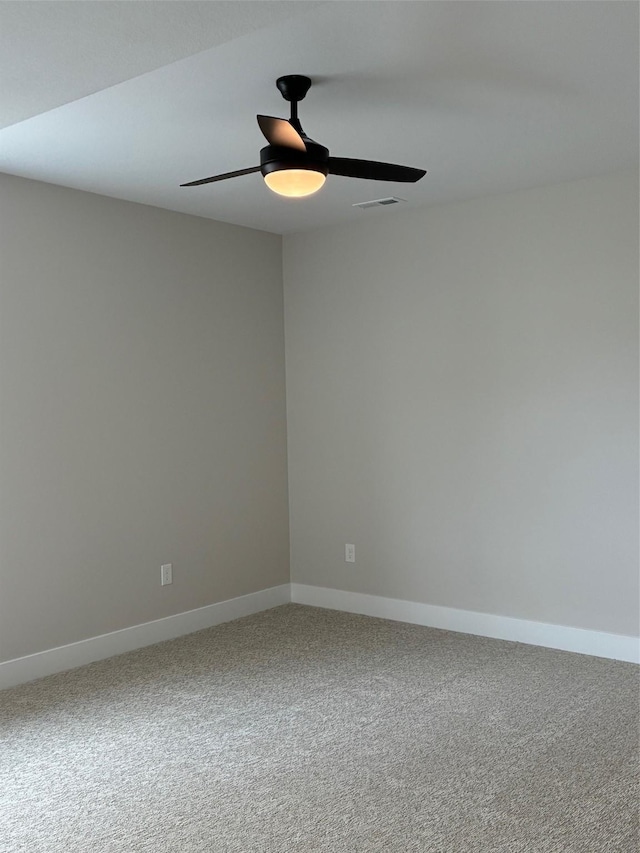 carpeted spare room with baseboards, visible vents, and a ceiling fan