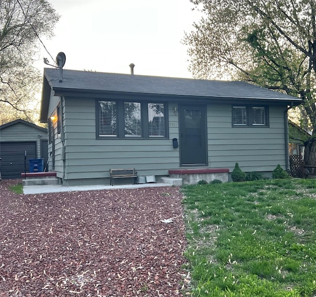 ranch-style home with a front yard, an outdoor structure, and a detached garage