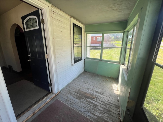 unfurnished sunroom featuring plenty of natural light and arched walkways
