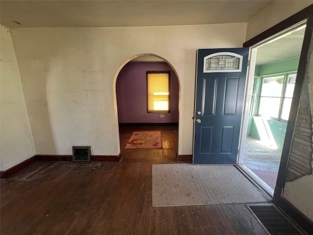 foyer featuring arched walkways, hardwood / wood-style floors, visible vents, and baseboards