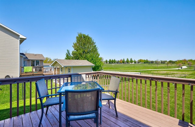 wooden deck featuring a yard, outdoor dining area, and an outbuilding