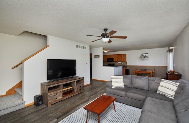 living room featuring visible vents, dark wood-style flooring, baseboards, and stairway