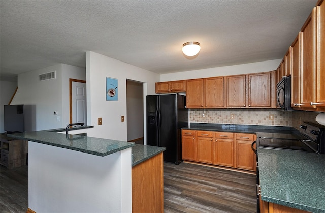 kitchen featuring dark wood-style flooring, visible vents, brown cabinets, black appliances, and tasteful backsplash