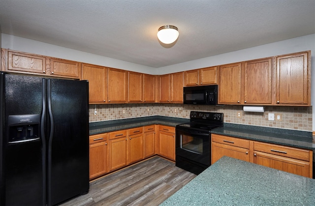 kitchen featuring decorative backsplash, brown cabinets, wood finished floors, and black appliances