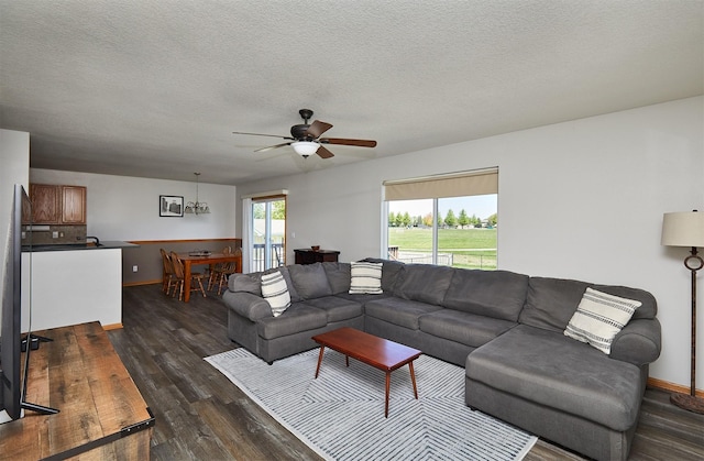 living room with baseboards, ceiling fan, a textured ceiling, and dark wood-type flooring