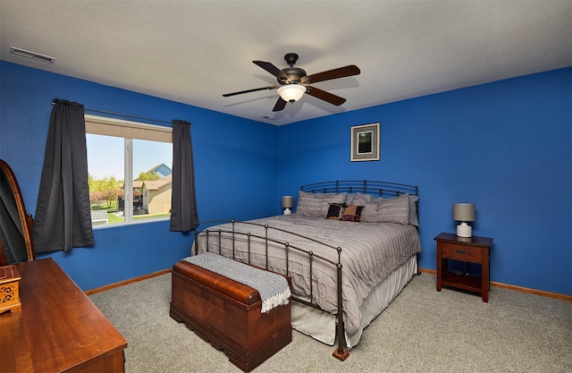 carpeted bedroom featuring baseboards, a textured ceiling, visible vents, and a ceiling fan