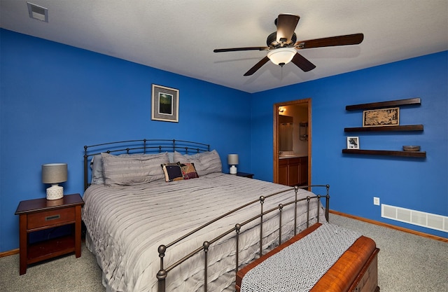 carpeted bedroom featuring ceiling fan, ensuite bathroom, baseboards, and visible vents