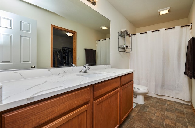 bathroom with vanity, toilet, and stone finish flooring