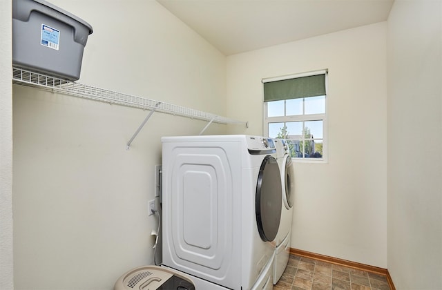laundry area featuring baseboards, stone finish floor, laundry area, and washer and dryer