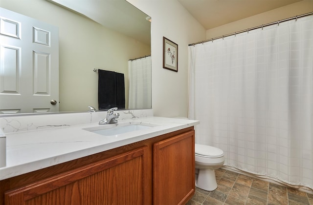 full bath featuring vanity, toilet, and stone finish flooring