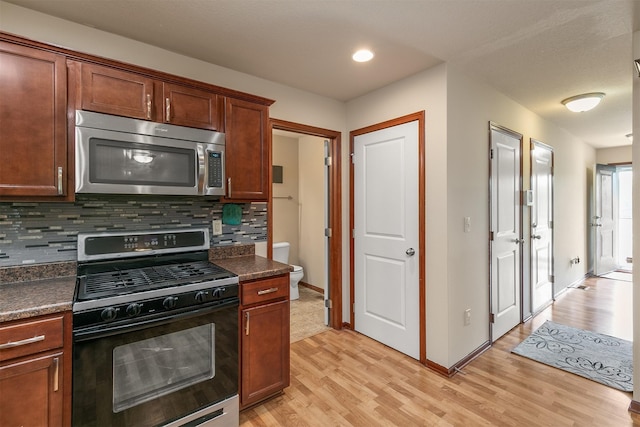 5301 SE 27th St, Des Moines, IA 50320 - kitchen with stainless steel microwave, black gas stove, dark countertops, tasteful backsplash, and light wood-style floors