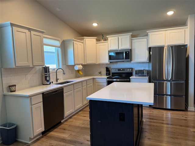 2708 NW Boulder Point Pl, Ankeny, IA 50023 - kitchen with vaulted ceiling, a sink, wood finished floors, light countertops, and appliances with stainless steel finishes