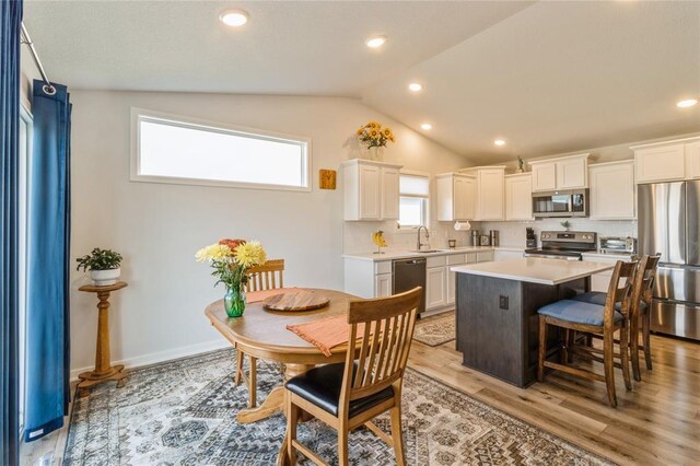 2708 NW Boulder Point Pl, Ankeny, IA 50023 - kitchen with lofted ceiling, stainless steel appliances, a sink, light countertops, and white cabinets