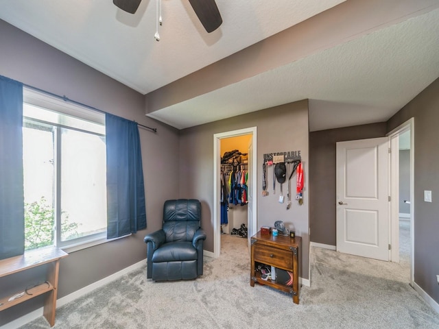 living area featuring ceiling fan, carpet, baseboards, and a healthy amount of sunlight
