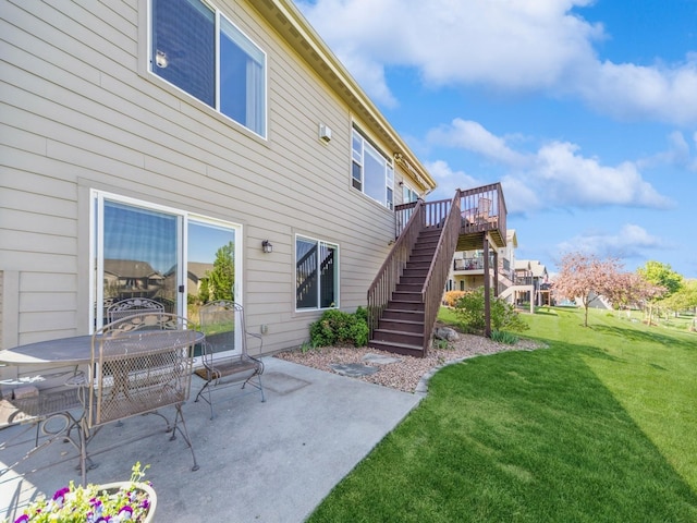 rear view of house with a lawn, stairway, a patio, and a wooden deck
