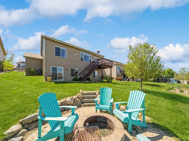 back of house featuring an outdoor fire pit, a deck, stairway, and a lawn