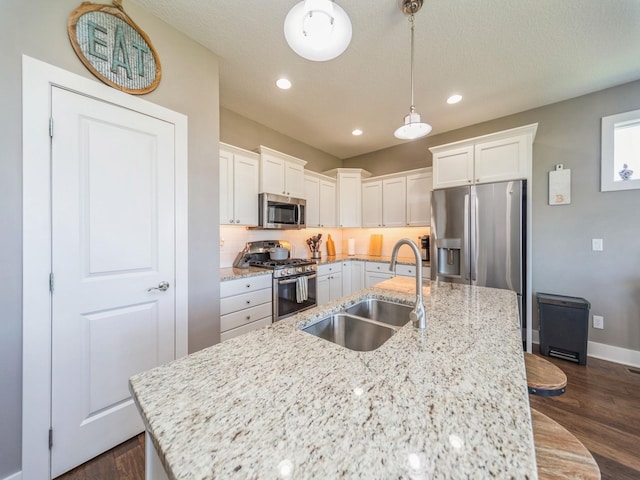 kitchen with a sink, dark wood-style flooring, stainless steel appliances, and a center island with sink