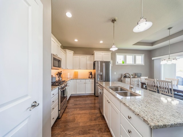 kitchen featuring a sink, stainless steel appliances, pendant lighting, a kitchen island with sink, and dark wood-style flooring