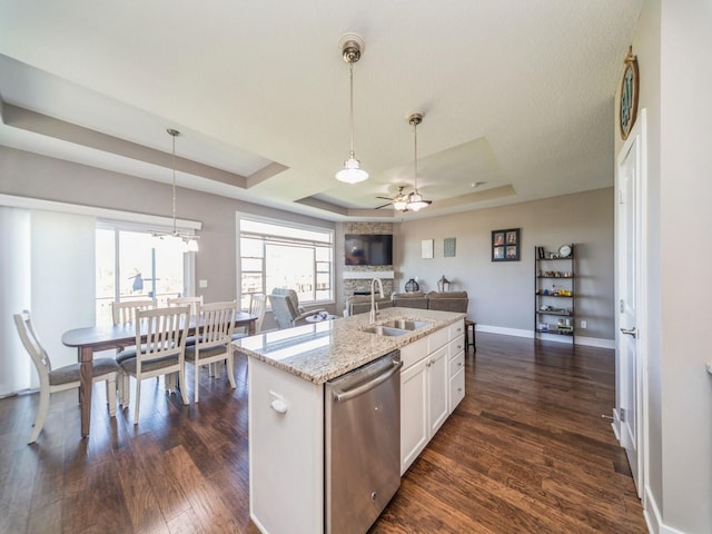 kitchen with ceiling fan with notable chandelier, a sink, a tray ceiling, dishwasher, and dark wood-style floors