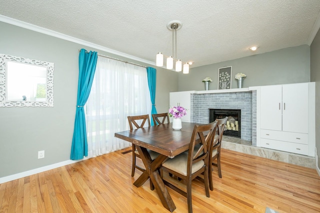 dining space with a textured ceiling, a brick fireplace, light wood-type flooring, and plenty of natural light