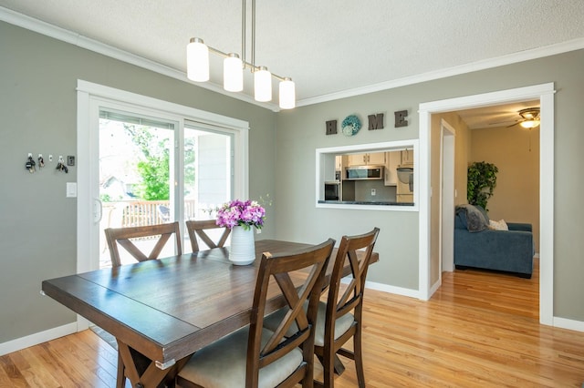 dining area with ornamental molding, a textured ceiling, baseboards, and light wood-style flooring