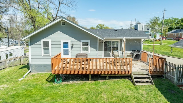 back of house with a yard, roof with shingles, fence, and a deck