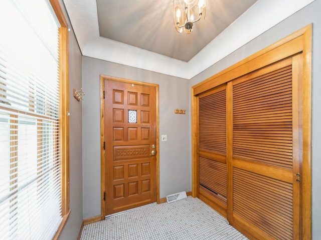 entryway with light colored carpet, baseboards, a notable chandelier, and visible vents