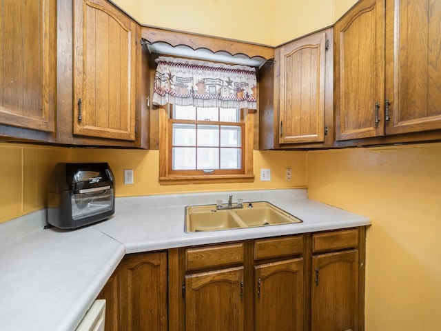 kitchen featuring a sink, brown cabinetry, and light countertops
