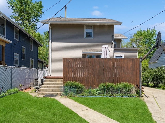 rear view of property featuring fence and a lawn
