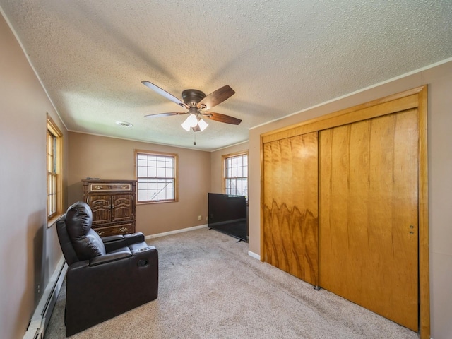 living area featuring carpet flooring, a baseboard radiator, ceiling fan, and a textured ceiling
