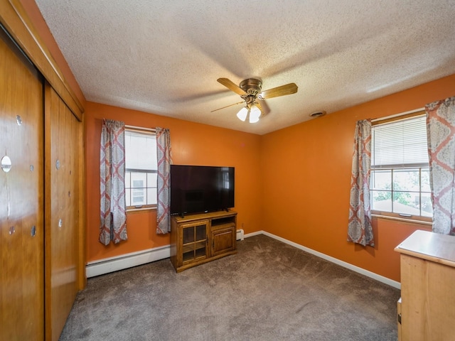 unfurnished living room with a textured ceiling, carpet flooring, a ceiling fan, and baseboard heating