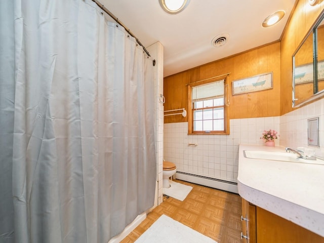 full bathroom featuring tile walls, toilet, vanity, visible vents, and a baseboard radiator