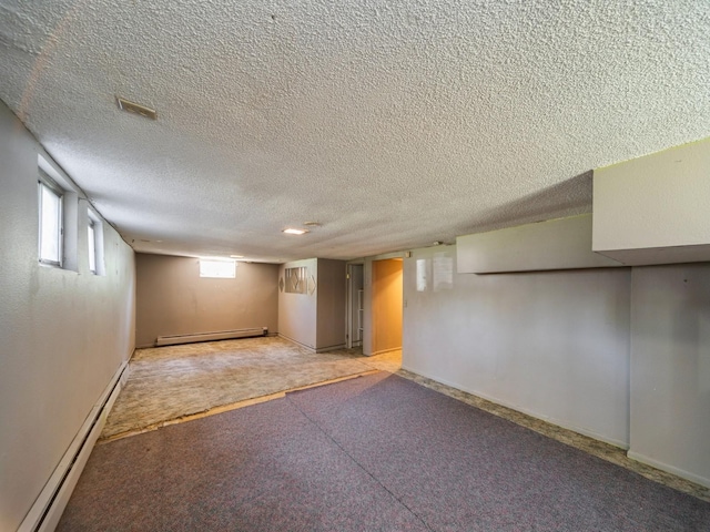 below grade area featuring a textured ceiling, carpet flooring, and a baseboard heating unit