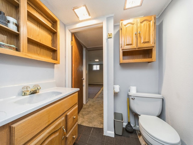 bathroom with toilet, vanity, and a baseboard heating unit