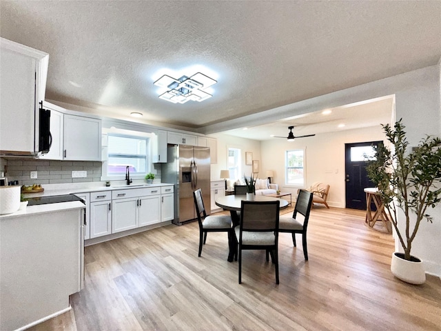 dining room with light wood finished floors, a wealth of natural light, a textured ceiling, and a ceiling fan
