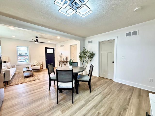 dining area featuring a textured ceiling, baseboards, light wood-type flooring, and visible vents