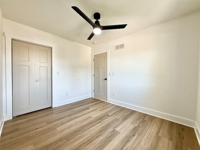 unfurnished bedroom with a closet, visible vents, light wood finished floors, ceiling fan, and baseboards