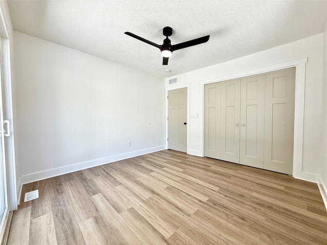 unfurnished bedroom with baseboards, light wood-style flooring, visible vents, and a textured ceiling