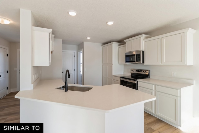 4112 NE 5th St, Ankeny, IA 50021 - kitchen with a sink, white cabinetry, a peninsula, light wood-style floors, and stainless steel appliances