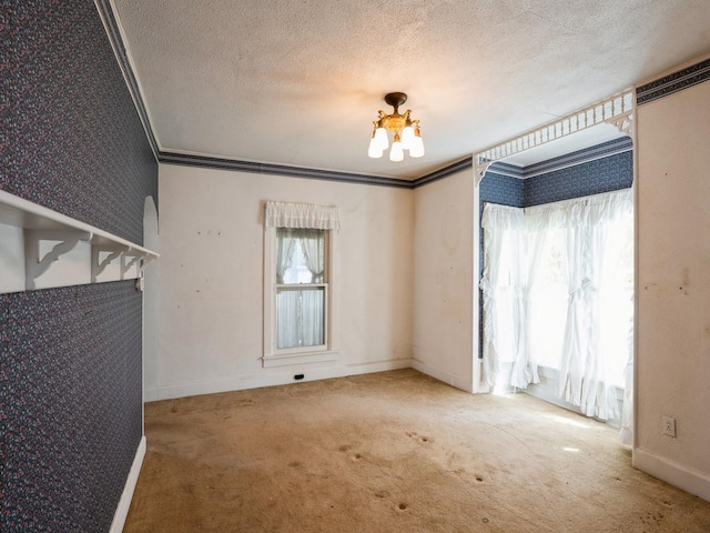 325 W 8th St S, Newton, IA 50208 - spare room with carpet flooring, a textured ceiling, a chandelier, crown molding, and baseboards