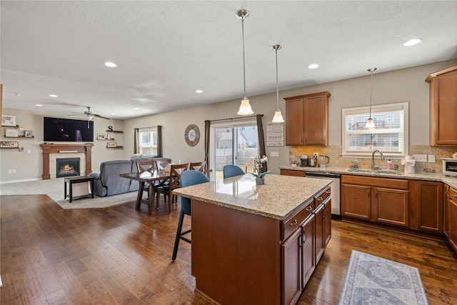270 NE Prairie Wolf Dr, Waukee, IA 50263 - kitchen with stainless steel dishwasher, a sink, a ceiling fan, a kitchen bar, and backsplash