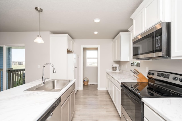 kitchen with white cabinetry, stainless steel appliances, light wood-type flooring, and a sink