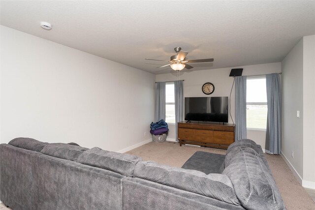 living area with light carpet, baseboards, and ceiling fan