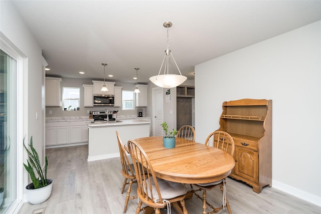 dining area with light wood-style flooring, baseboards, and recessed lighting