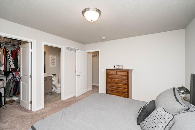bedroom featuring a closet, baseboards, visible vents, a spacious closet, and light colored carpet