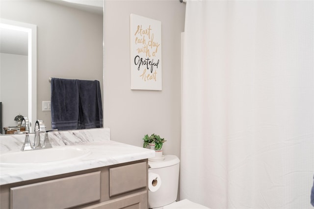 bathroom featuring curtained shower, vanity, and toilet