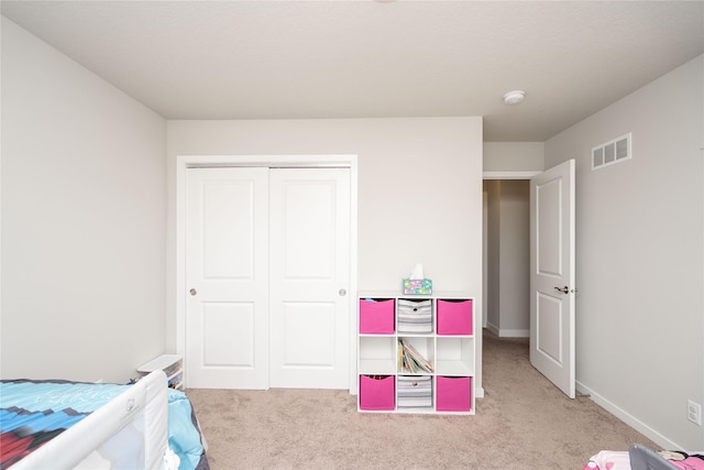 bedroom featuring baseboards, a closet, visible vents, and carpet