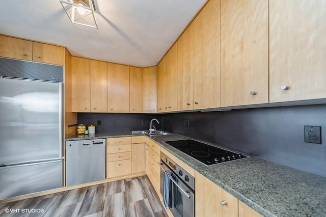 kitchen featuring appliances with stainless steel finishes, wood finished floors, light brown cabinets, and a sink
