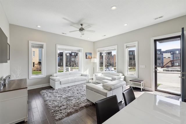living area featuring plenty of natural light, baseboards, a ceiling fan, and visible vents