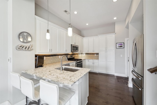 kitchen with recessed lighting, a sink, a peninsula, decorative backsplash, and appliances with stainless steel finishes